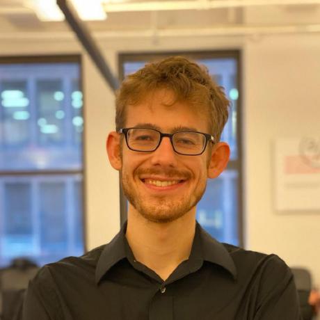 Photo of Patrick Landy, a man wearing glasses and a black dress shirt